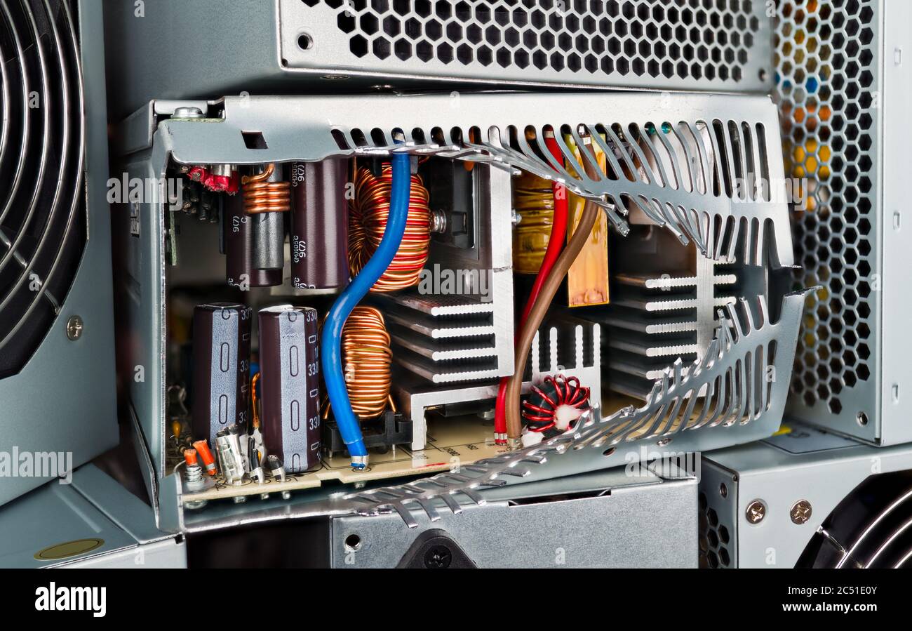 Close-up view of electronic components inside a computer power supply showing inductors, capacitors, transformers, and aluminum heatsinks